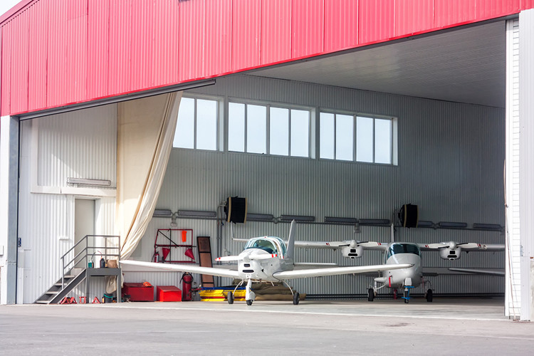 Interior view of column-free steel aircraft hangar showing industrial ventilation and lighting layout